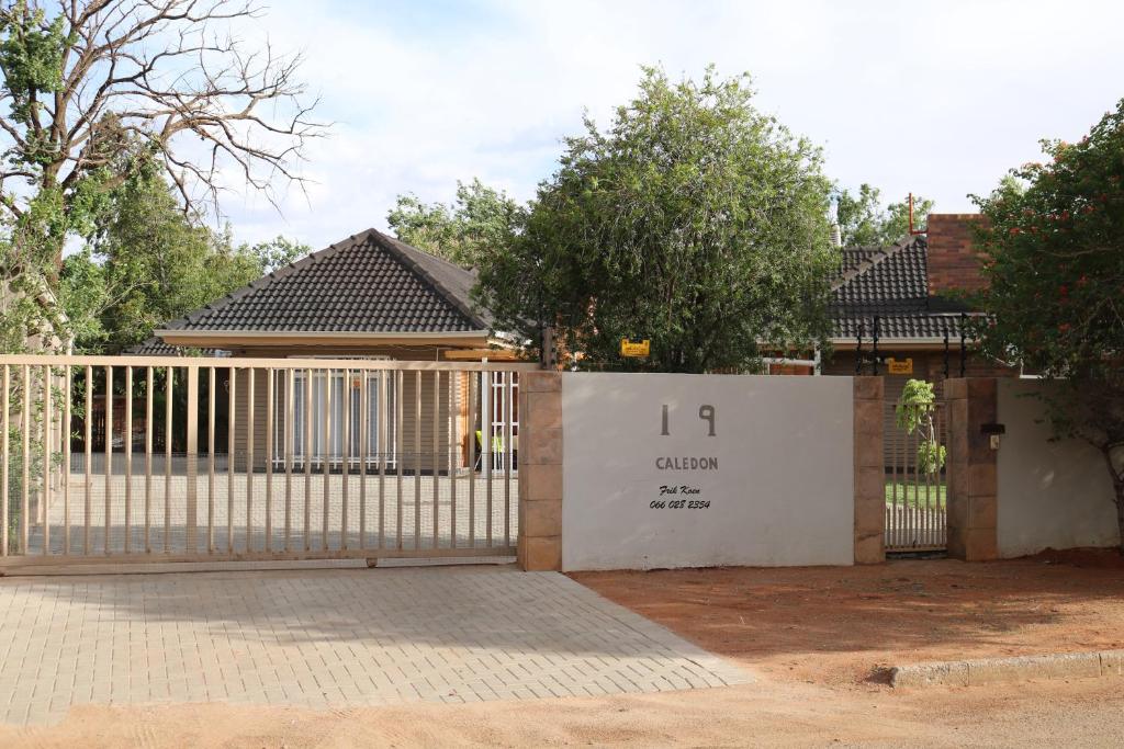 a white gate in front of a house at Caledon Overnight Rooms in Kimberley