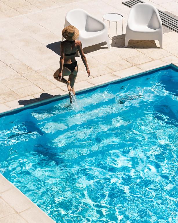 a man in a hat is jumping into a swimming pool at M2 Resort Wellness & Spa in Ostrowo