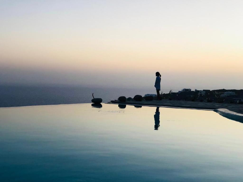 a person standing on the edge of a body of water at Luxury Villa Dorothea Mykonos in Fanari