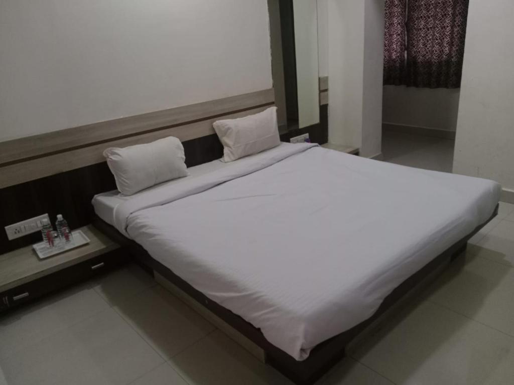 a large bed with white sheets and pillows on it at Hotel Paras in Junagadh