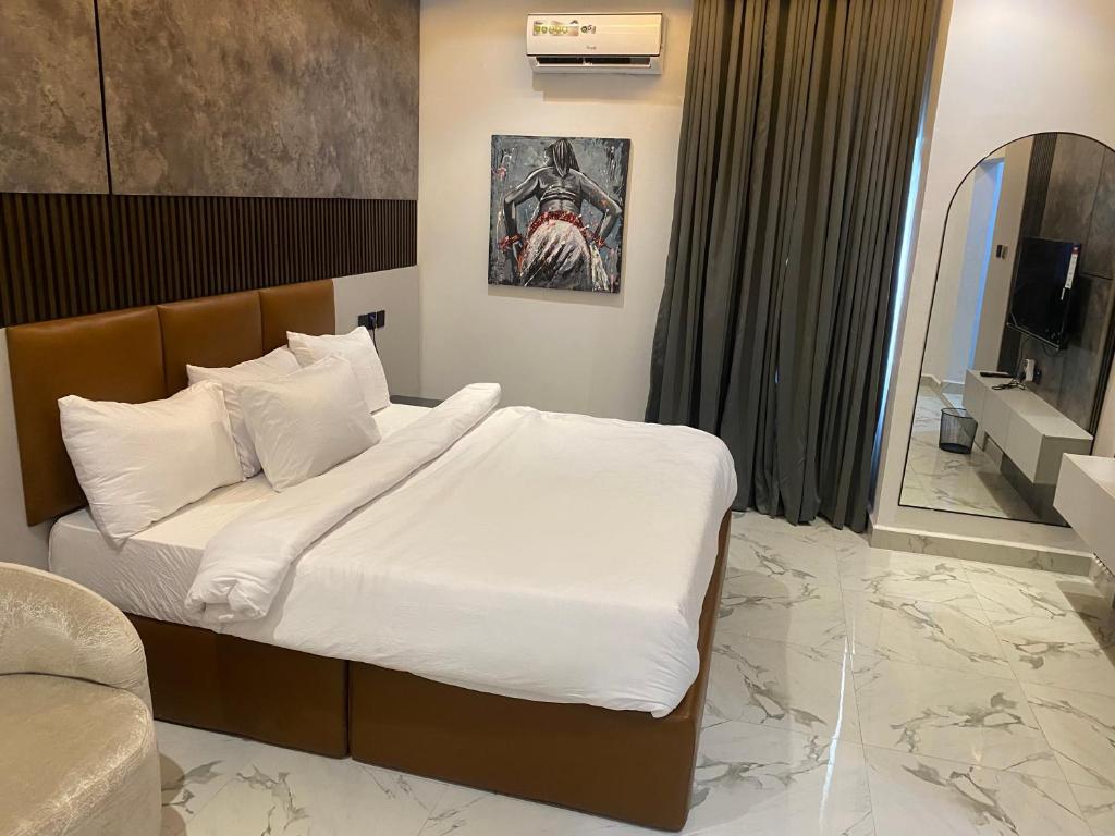 a bedroom with a bed with white sheets and a mirror at De Ark Inn hotel in Port Harcourt
