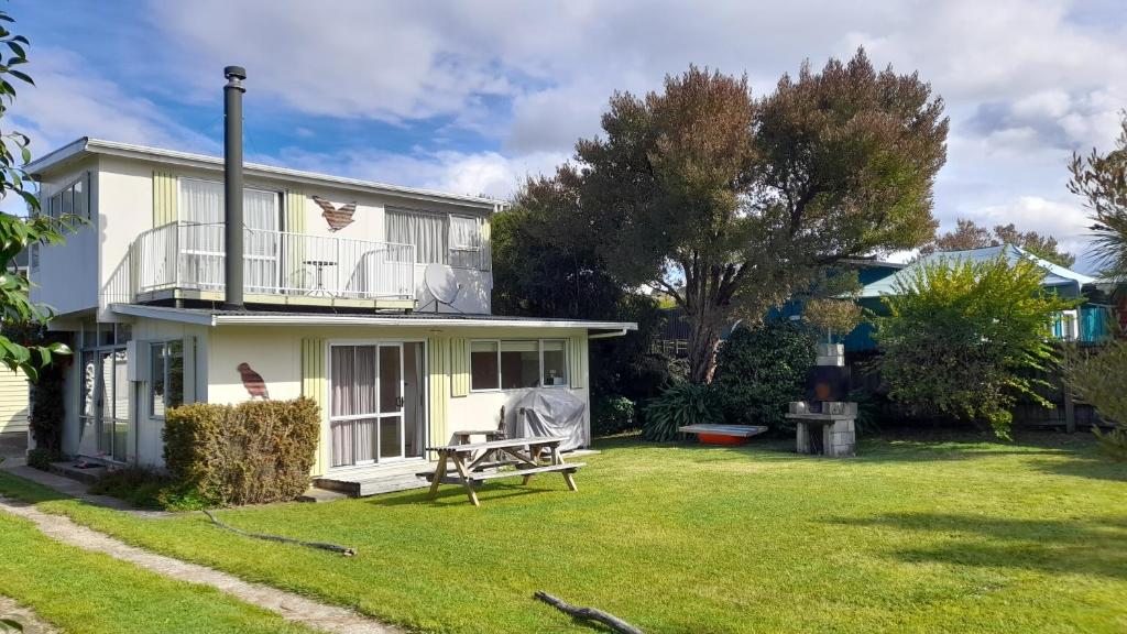 a white house with a bench in the yard at Kea View - Pohara Beach Holiday Home in Pohara