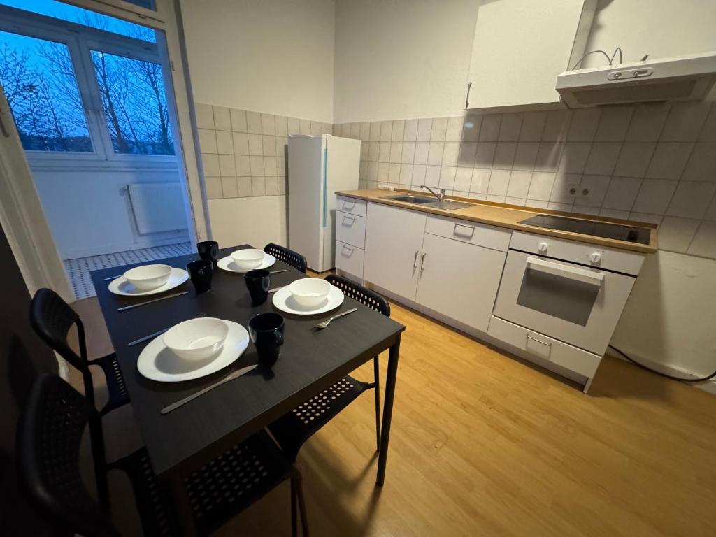 a kitchen with a black table and chairs and a kitchen with a refrigerator at Living - Ferien & Monteur Appartement in Wuppertal