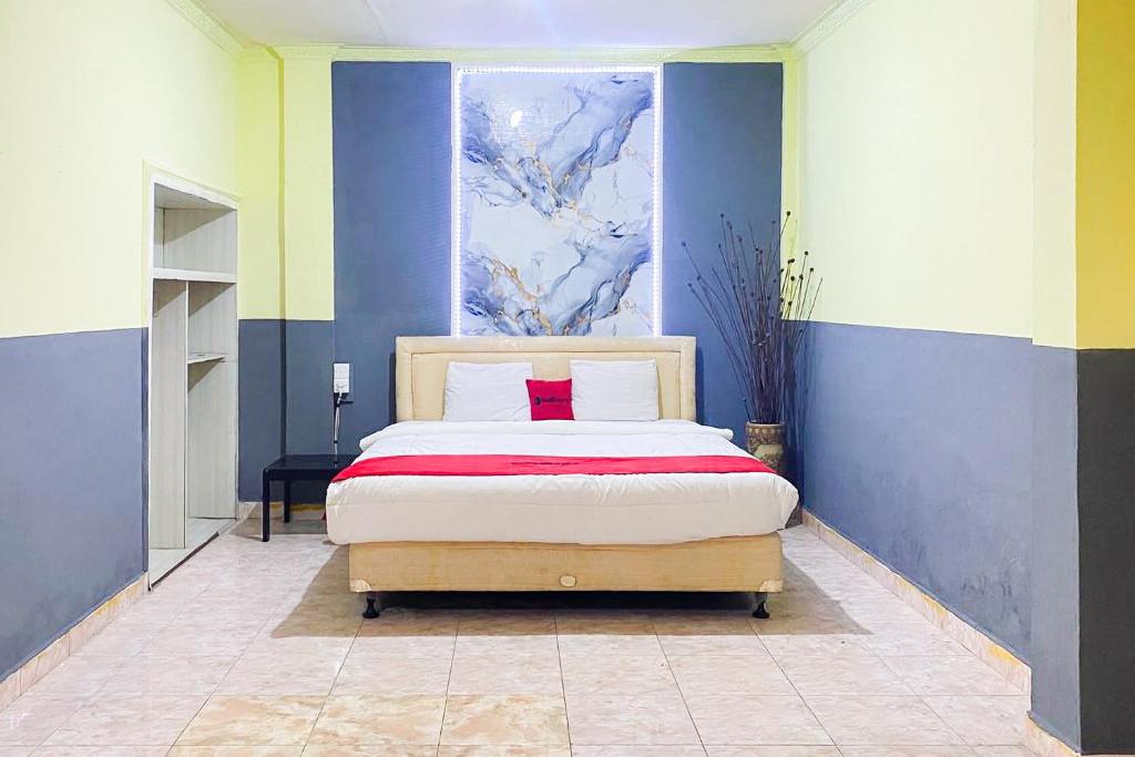 a bedroom with a bed with a painting on the wall at RedDoorz Syariah At Hotel Matahari 1 Jambi in Jambi