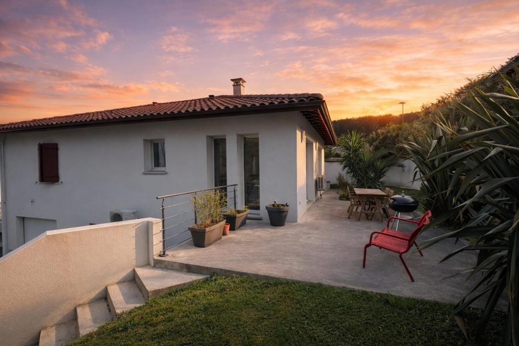 a white house with a red chair on a patio at La Parenthèse d'Hasparren - Avec Parking Privé in Hasparren