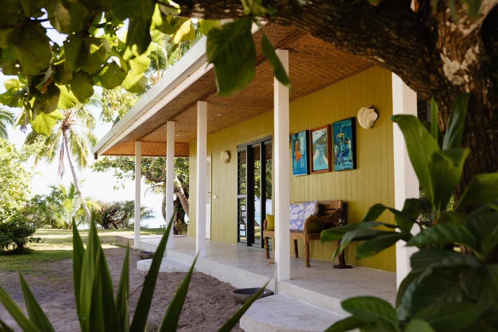 a house with yellow walls and a porch at Fare Teiti Beach Bungalow in Haapiti