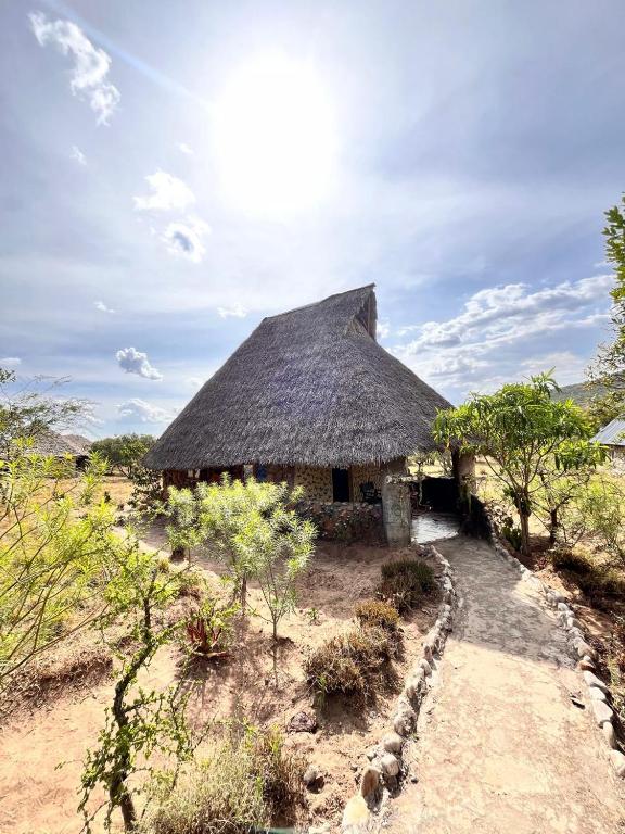 a hut with a thatched roof in a field at Eco Mara Tented Camp in Ololaimutiek