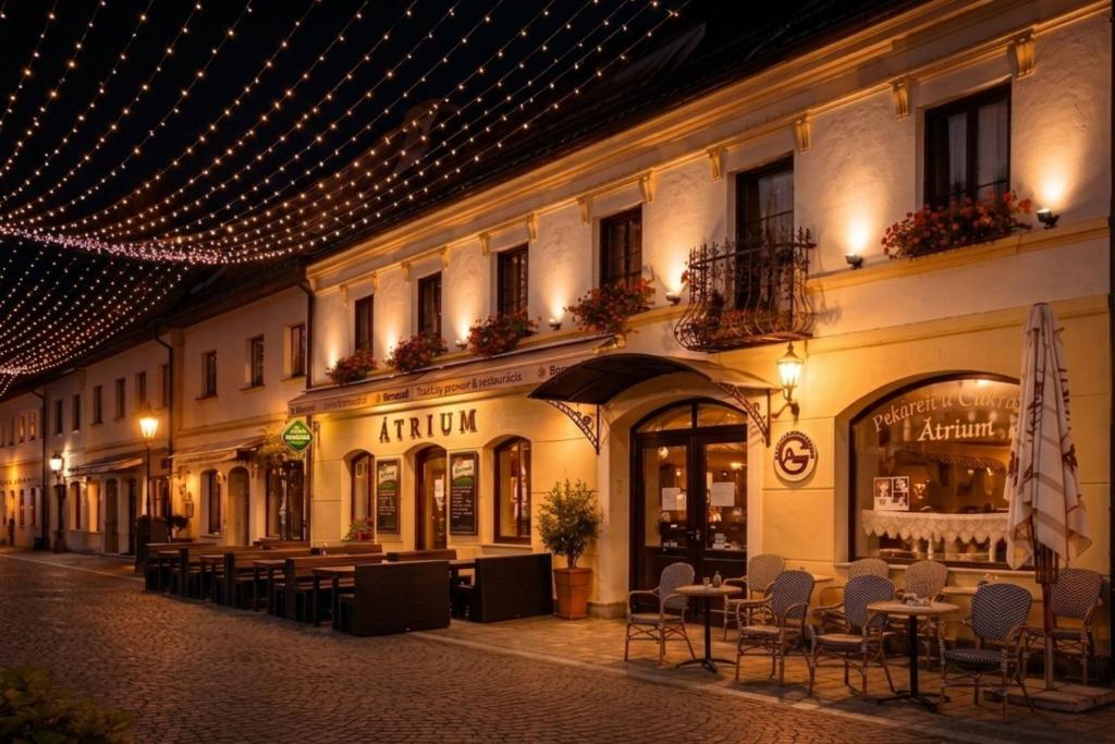 a building with tables and chairs on a street at night at Penzión ÁTRIUM in Prešov