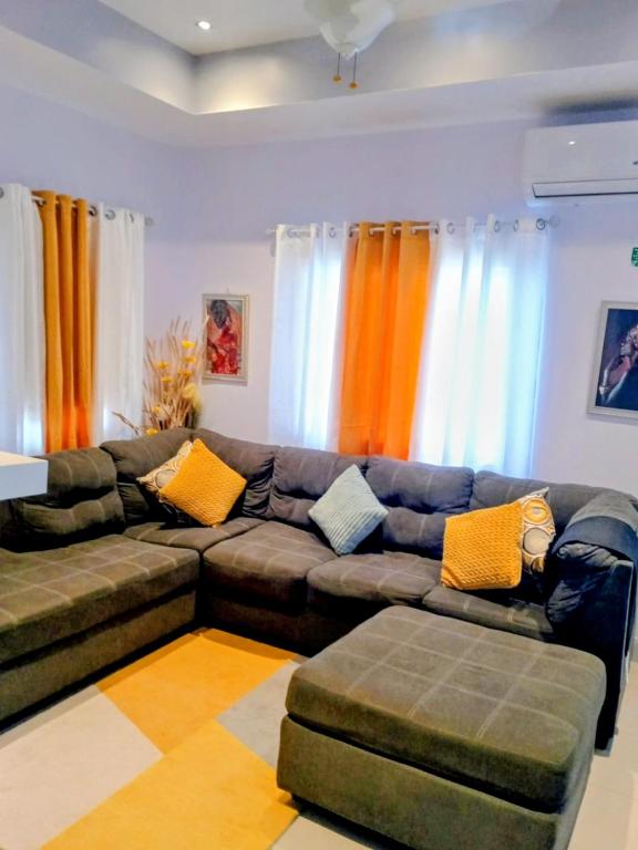 a living room with a brown couch and orange curtains at Summer Breeze Villa in Lucea