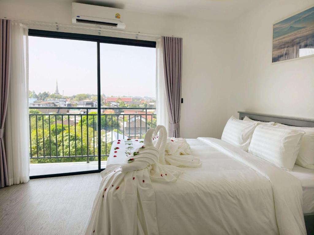 a bedroom with a white bed with a large window at The View Hotel โรงแรมเดอะวิว นครศรีธรรมราช in Nakhon Si Thammarat