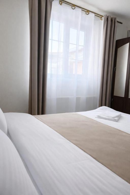a bedroom with a white bed and a window at Heaven Boutique in Pucioasa