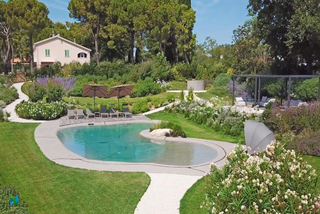 a swimming pool in a garden with grass and flowers at Villa Pietrarosa by MMega in Cascina Monte Serico