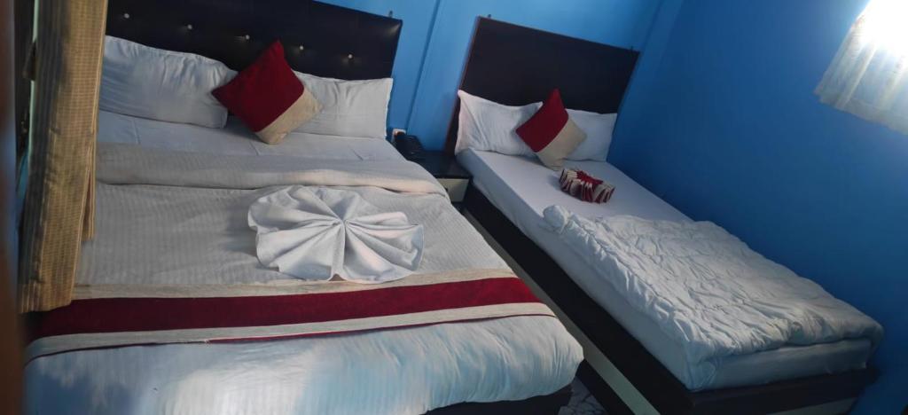 two twin beds in a blue room withskirts at Hotel Aahar chitawan in Bharatpur