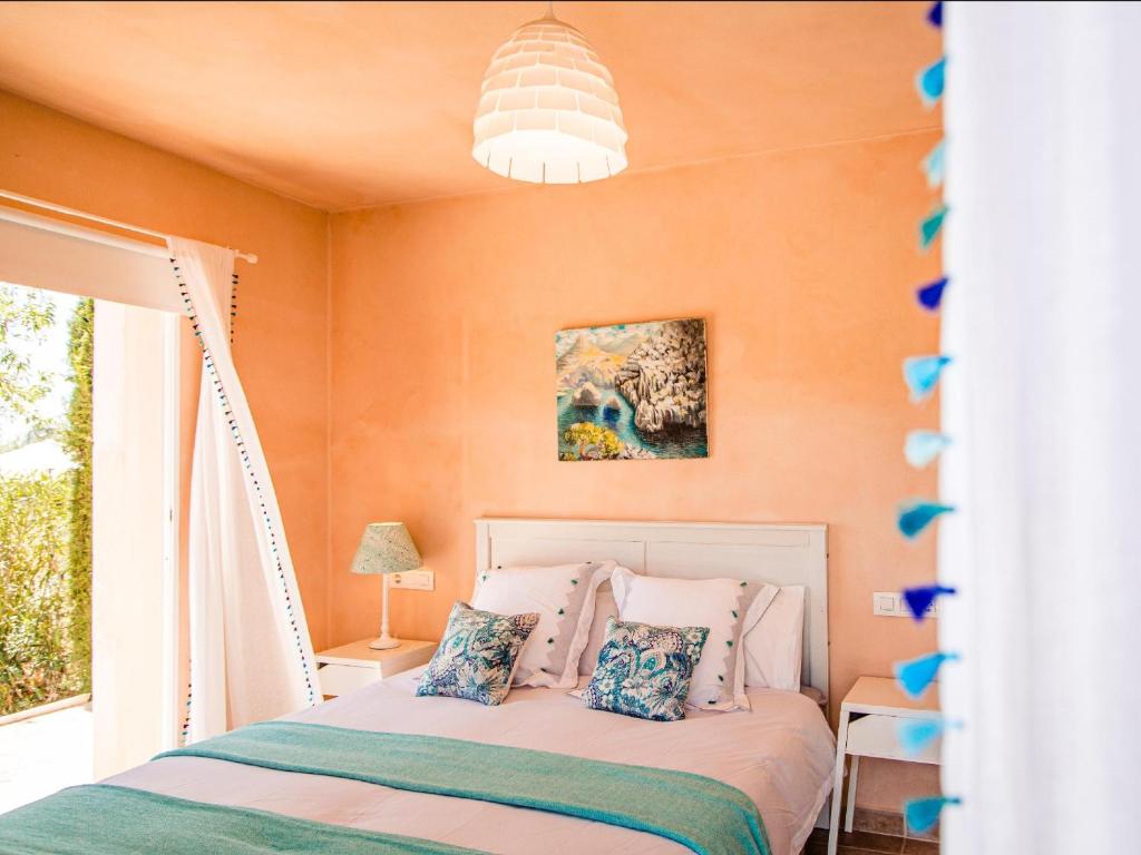 a bedroom with orange walls and a bed with pillows at Finca Bassa Serra in Santanyi