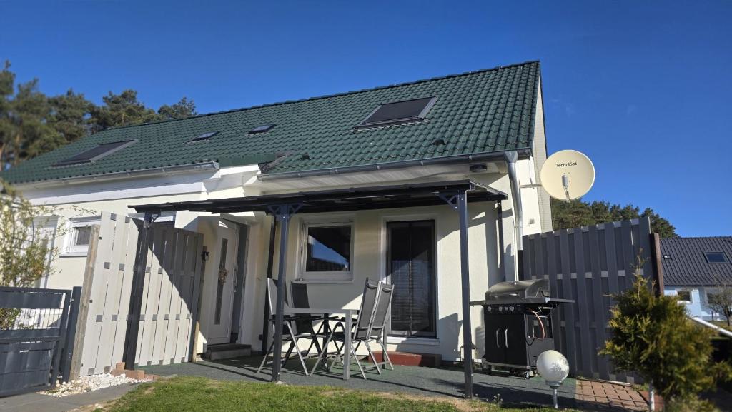 a small white house with a patio with a grill at Ferienhaus Köhler Am Achterwasser , Urlaub mit Hund in Lütow