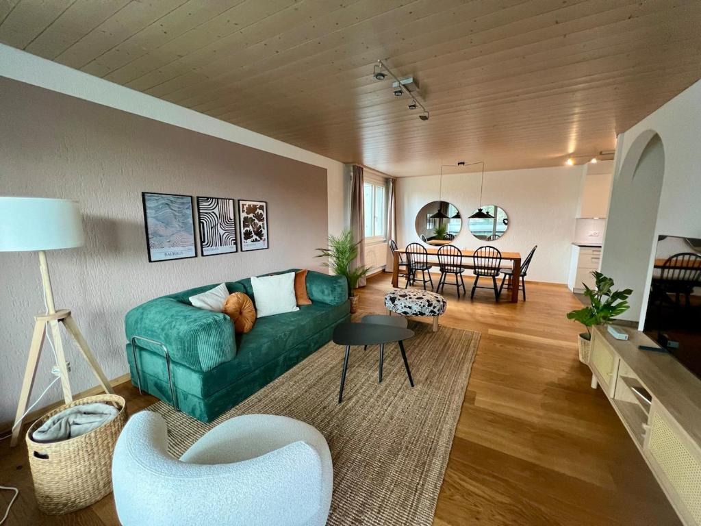 a living room with a green couch and chairs at Dock and Dwell City Appartment in Bern