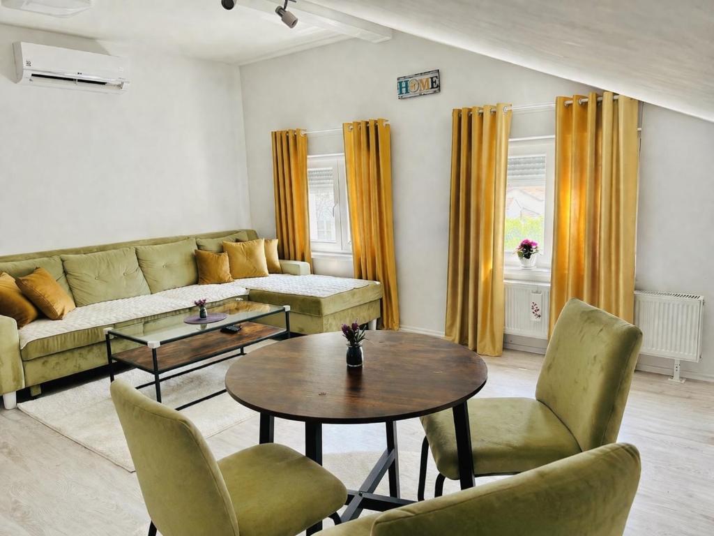 a living room with a couch and a table and chairs at Urban Gold Apartment in Mostar