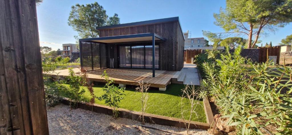 a small house with a wooden deck in a garden at Luxury Cottage Sauna&Pool at CapDAgde in Agde