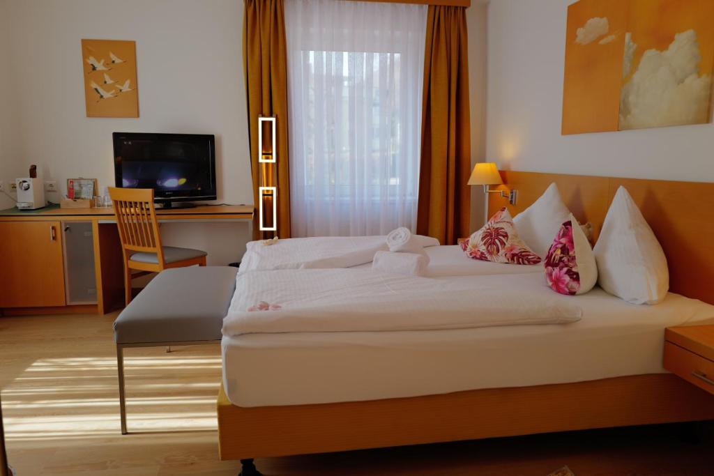 a bedroom with a bed and a desk and a television at Motel55 - nettes Hotel mit Self Check-In in Villach, Warmbad in Villach