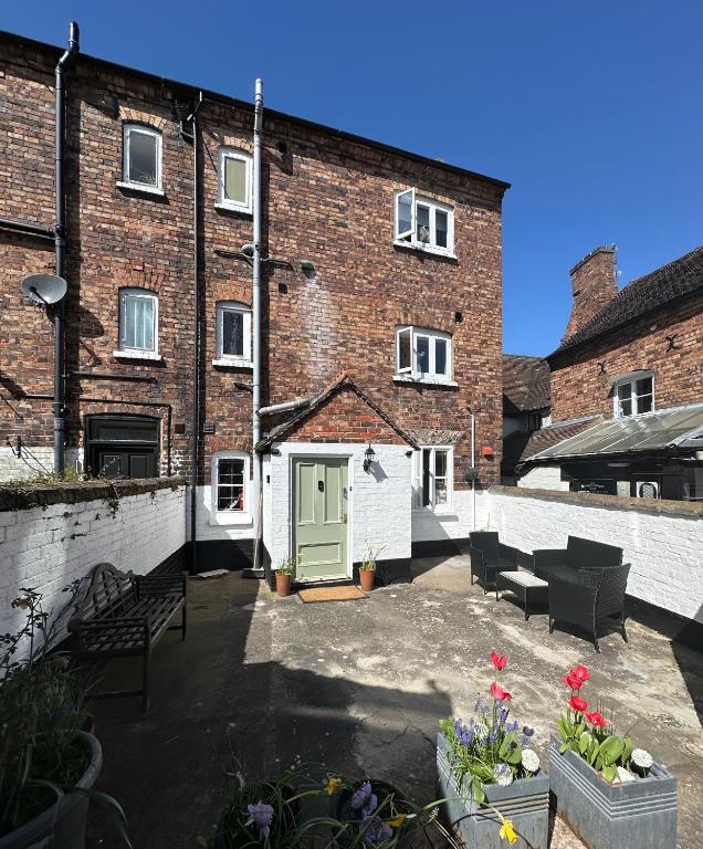 a brick building with a green door and a patio at Charming 3 Bedroom High St Apartment in Much Wenlock