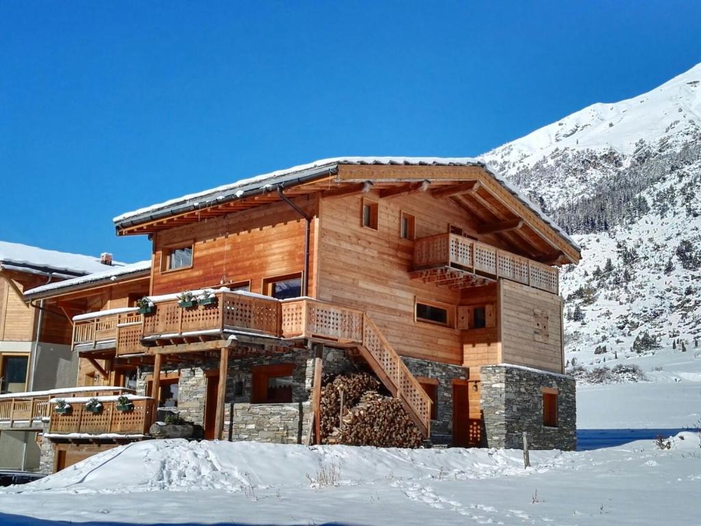 uma cabana de madeira na neve com montanhas cobertas de neve em Chalet Ciamarella em Lanslevillard