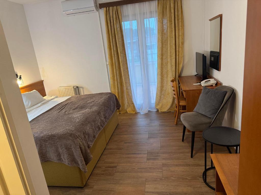 a bedroom with a bed and a desk and a chair at Hotel Žućo in Biograd na Moru