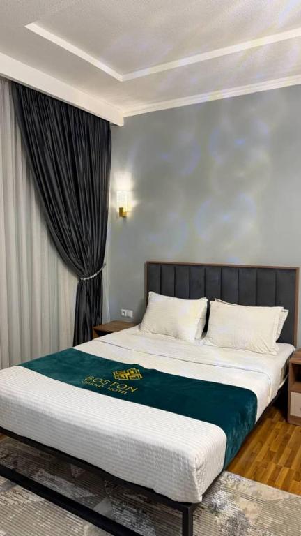 a bedroom with a bed with a blue blanket on it at Boston Grand hotel in Osh