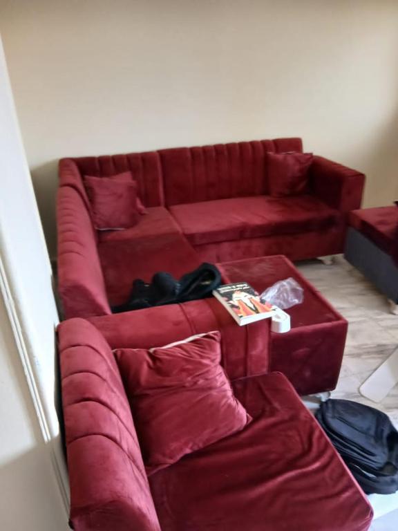 a red couch sitting in a living room at Share Apartment but Private Room in Madinat Al Ashir min Ramadan