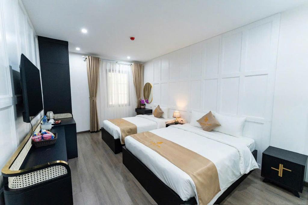 a hotel room with two beds and a television at HoangAnh Hotel in Ha Long