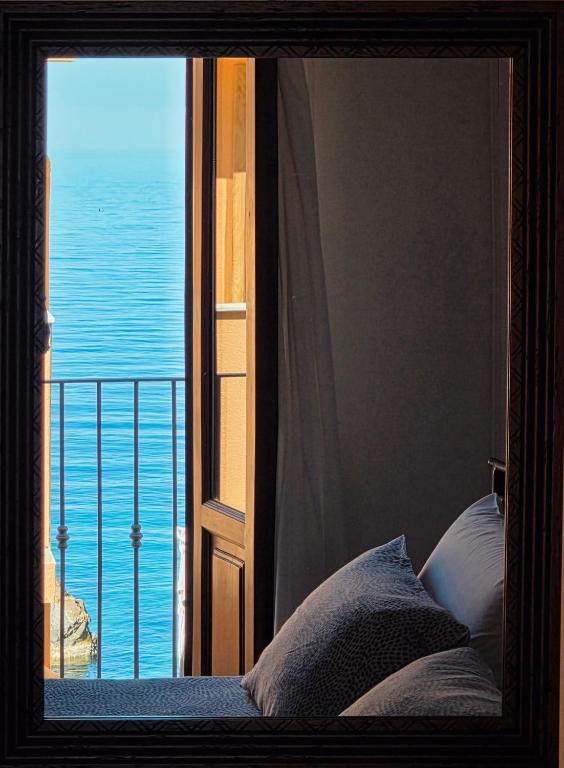a bedroom with a window with a view of the ocean at LA CASETTA AZZURRA CHIANALEA - locazione turistica in Scilla