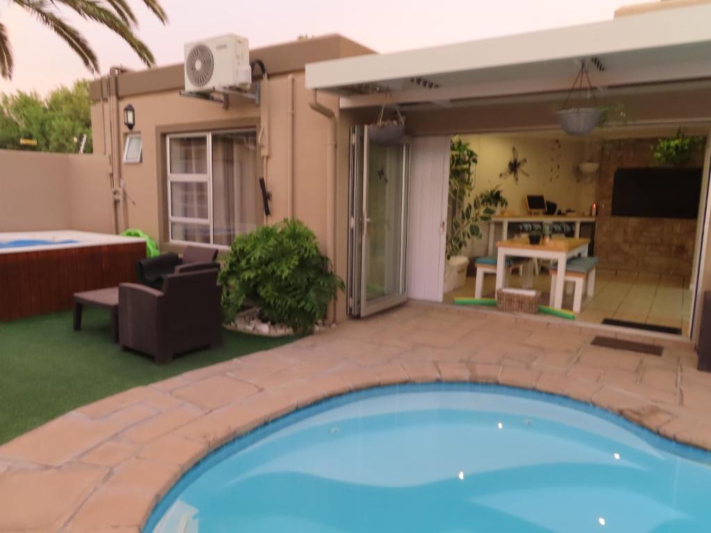 a swimming pool in the backyard of a house at AquaPalms Hideaway - Family Friendly Pool - Hot Tub - Indoor Braai in Cape Town