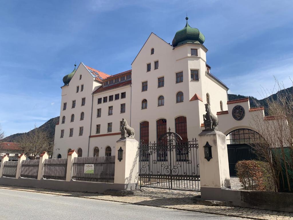 a large white building with a fence in front of it at Ferienwohnungen Haus Castello App9 in Aschau im Chiemgau