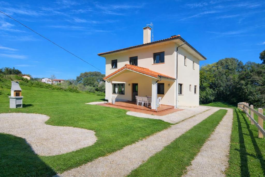 a small white house on a hill with a fence at Casa en Llanes con jardín - Huergo Mar y Playa in Nueva de Llanes