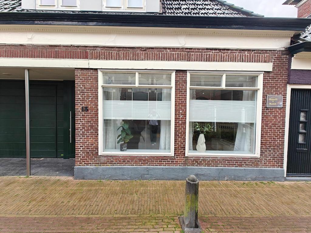 a brick house with a white cat sitting in a window at Studio 13 in Dronrijp