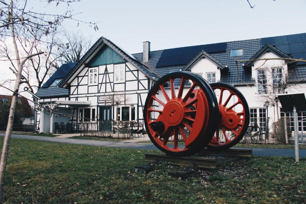 a sculpture of a wagon wheel in front of a house at Alter Bahnhof Sichtigvor in Warstein