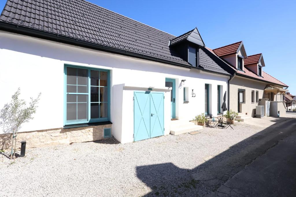 a white house with a blue door on the side of it at Hofgassenhaus LIMUN in Mörbisch am See