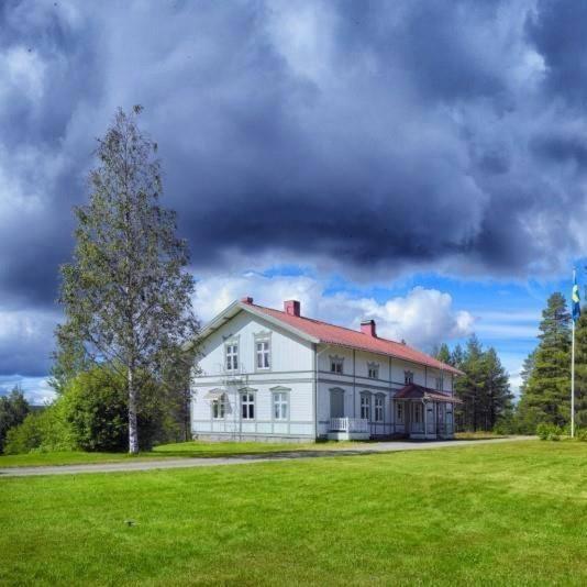 a large white house with a tree in a field at Lantlivlodge i Österjörn -Herrgård in Österjörn