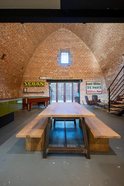 a large wooden table in a room with a brick wall at Le Magasin à Poudre in Rocroi