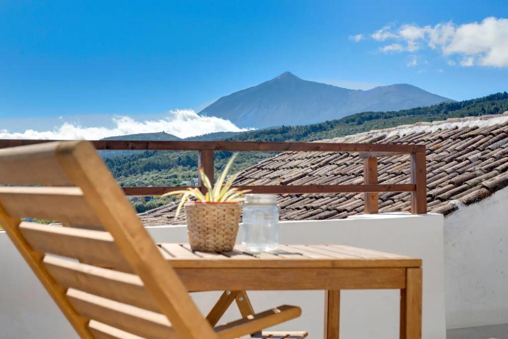 a wooden chair on a balcony with a view of mountains at La Paredita Casa Guimar in Tanque