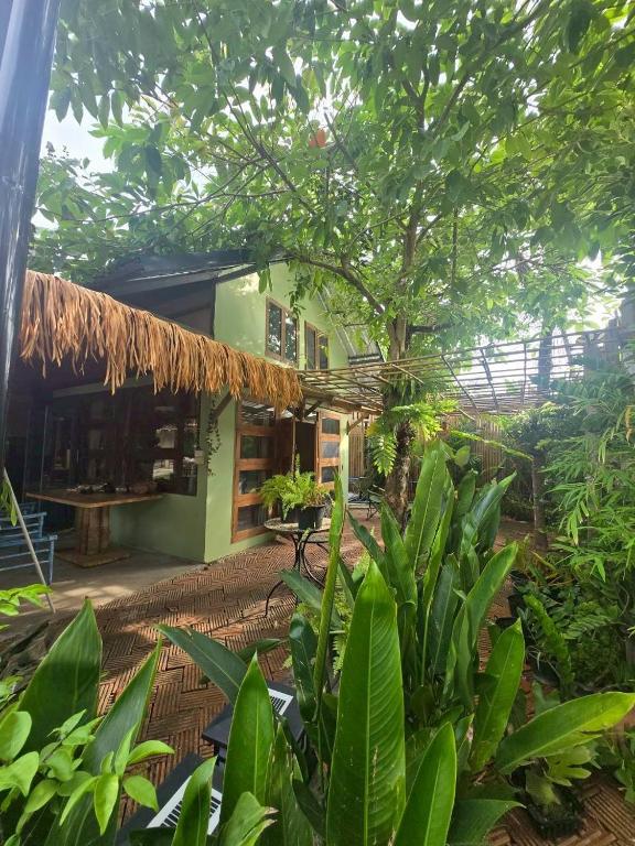 a tropical garden with a building with a tree at Three Hen Lakeside in Ban Na Nai