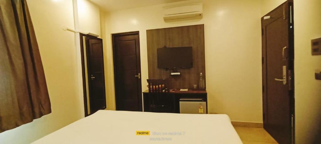 a hotel room with a bed and a television at Theni hotel ramyas in Theni