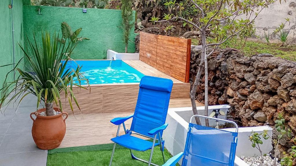 a pool with two blue chairs and a plant at GuestReady - El Pinar isla del Hierro in El Pinar del Hierro