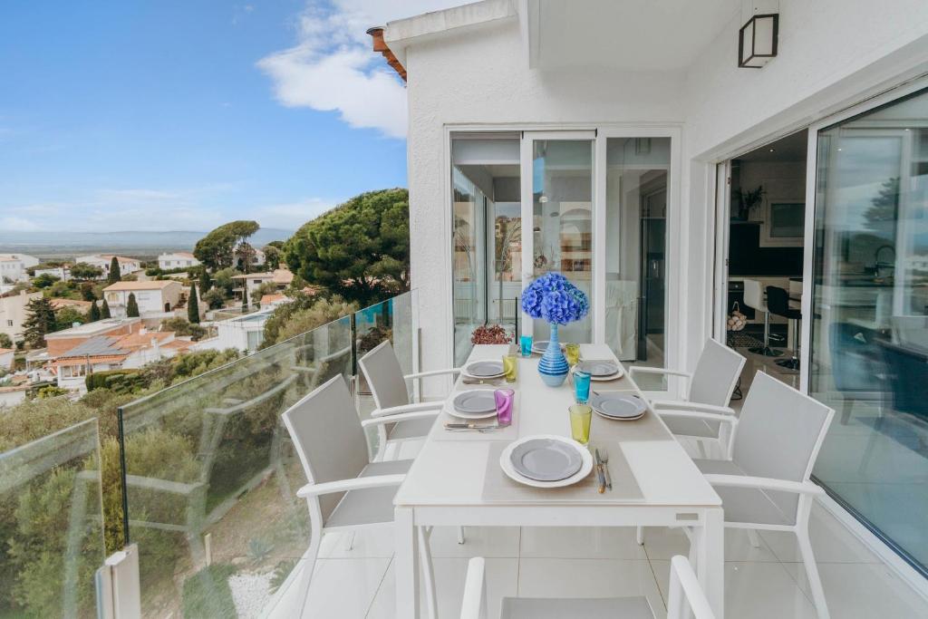 a white dining table and chairs on the balcony of a house at WELCS CASA 335 EMP con jacuzzi y terraza in Selva de Mar