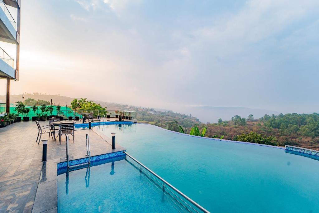 a swimming pool with tables and chairs on a building at Ritz Valley Resort in Mahabaleshwar