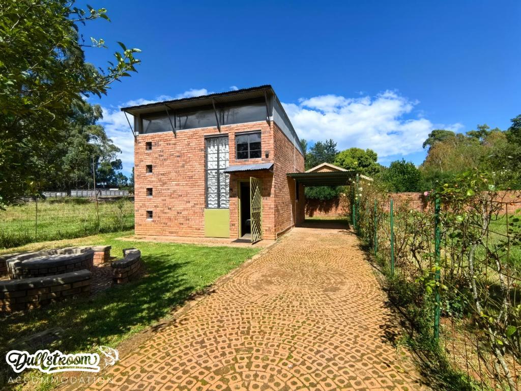 a brick building with a black roof on a field at Olive Branch in Dullstroom
