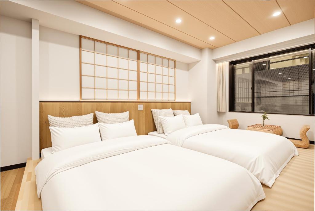 two white beds in a room with a window at YCYC Hotel in Tokyo