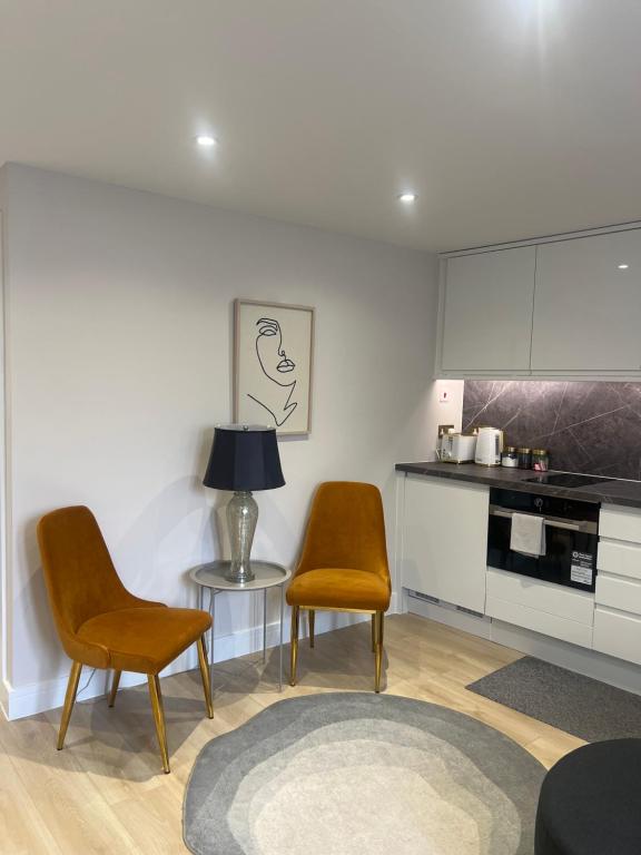 a kitchen with two chairs and a table with a lamp at Brand New One Bedroom Apartment in Hendon