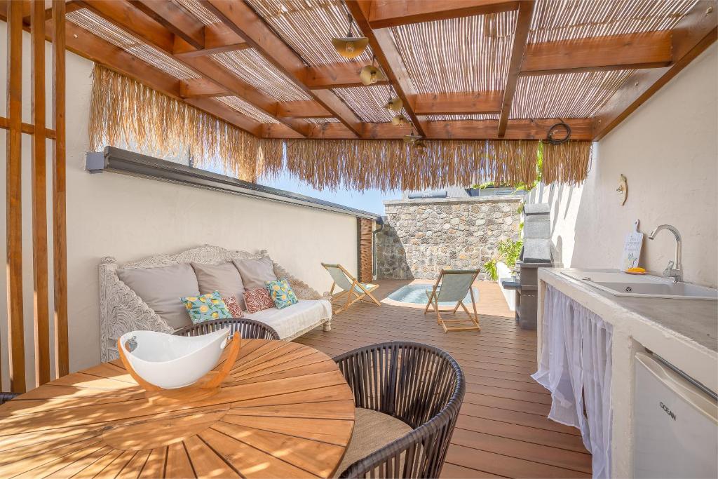a patio with a table and chairs and a couch at Ô Bel Appart, piscine privée & BBQ, ambiance balinaise in Les Cocos
