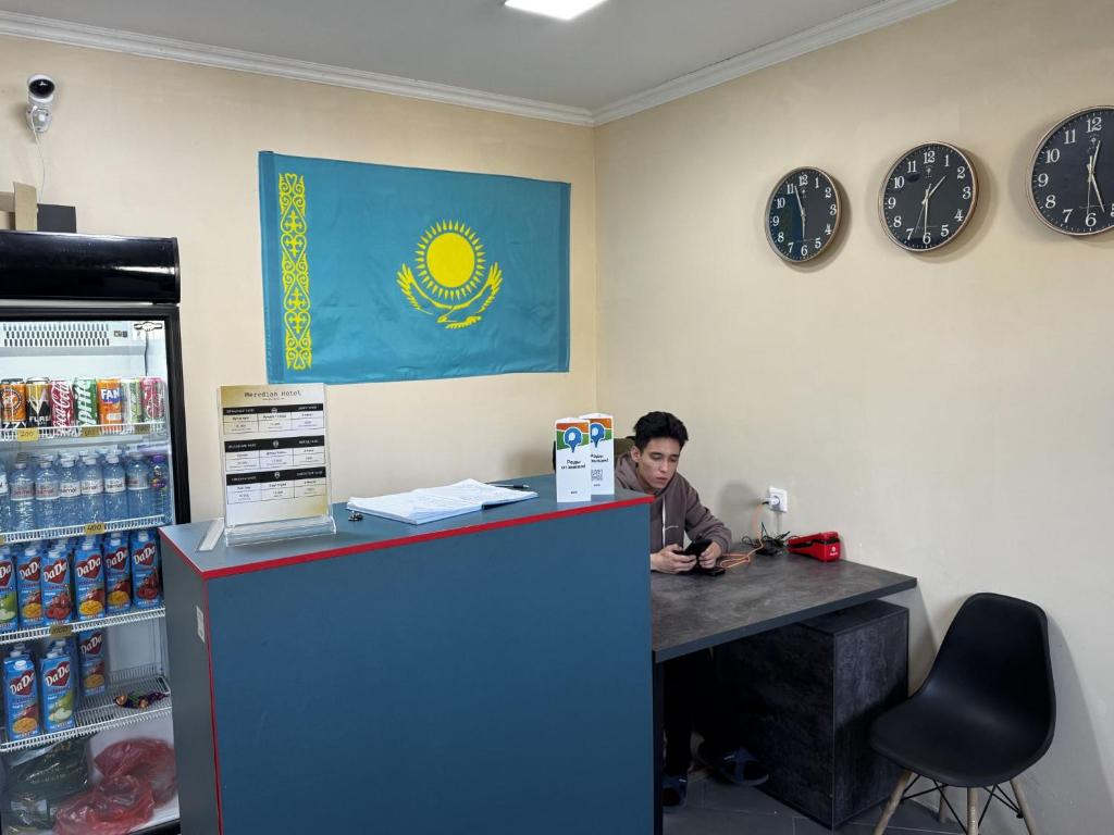 a man is sitting at a counter in a coffee shop at Meridian Hostel in Almaty