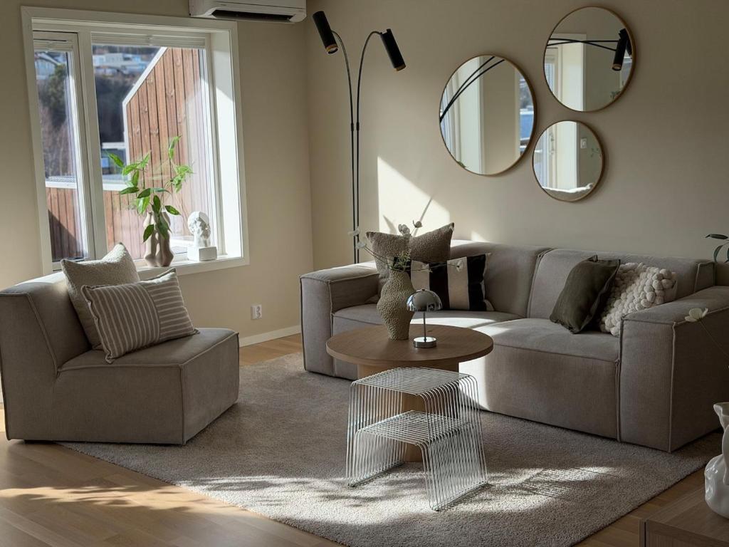 a living room with a couch and a table and mirrors at Modern and stylish home in Bergen